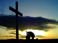 A Christian Demo Service guitarist kneels at the foot of the cross